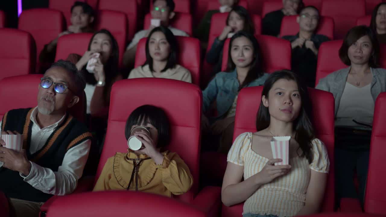 亚洲华人活跃的老人和孙女喜欢在电影院看恐怖电影视频素材