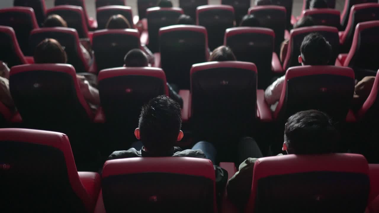 后视组亚洲观众在电影院观看3D电影，戴上3D眼镜欣赏演出视频素材