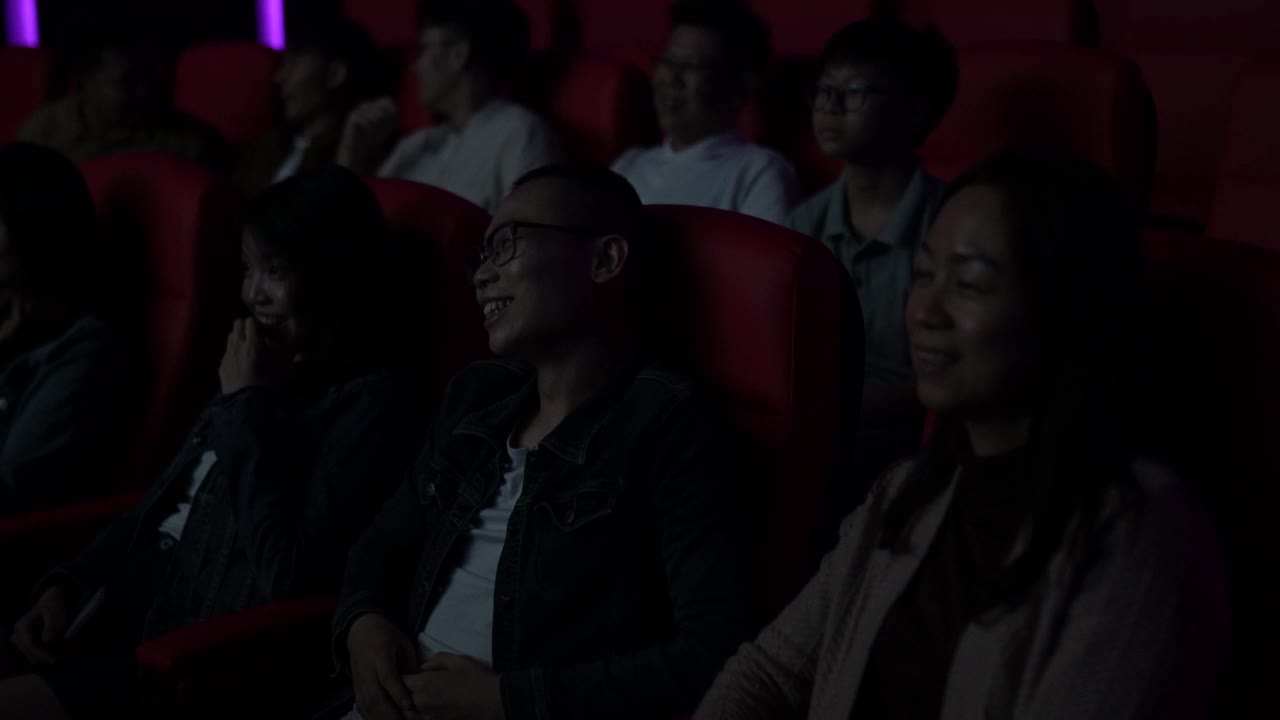 一位亚洲华人母亲和她的孩子在电影院看喜剧电影视频下载