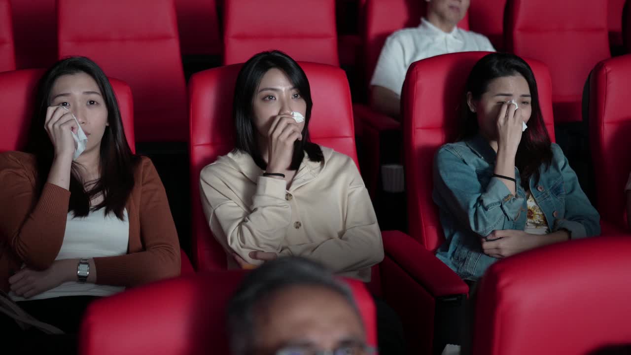 亚洲的中国女性朋友在电影院看感伤的电影，在电影院用纸巾擦眼泪视频下载