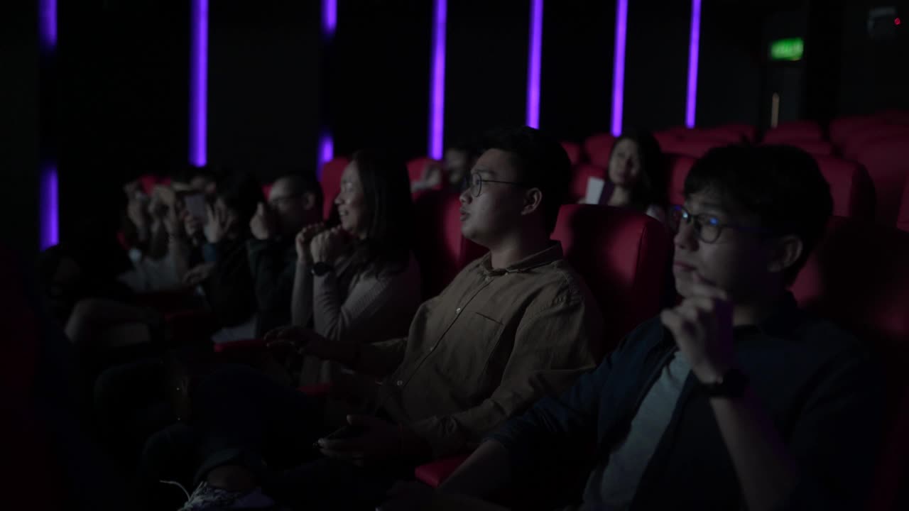 亚洲华人混合年龄段的观众在电影院排成一排享受和观看电影视频下载