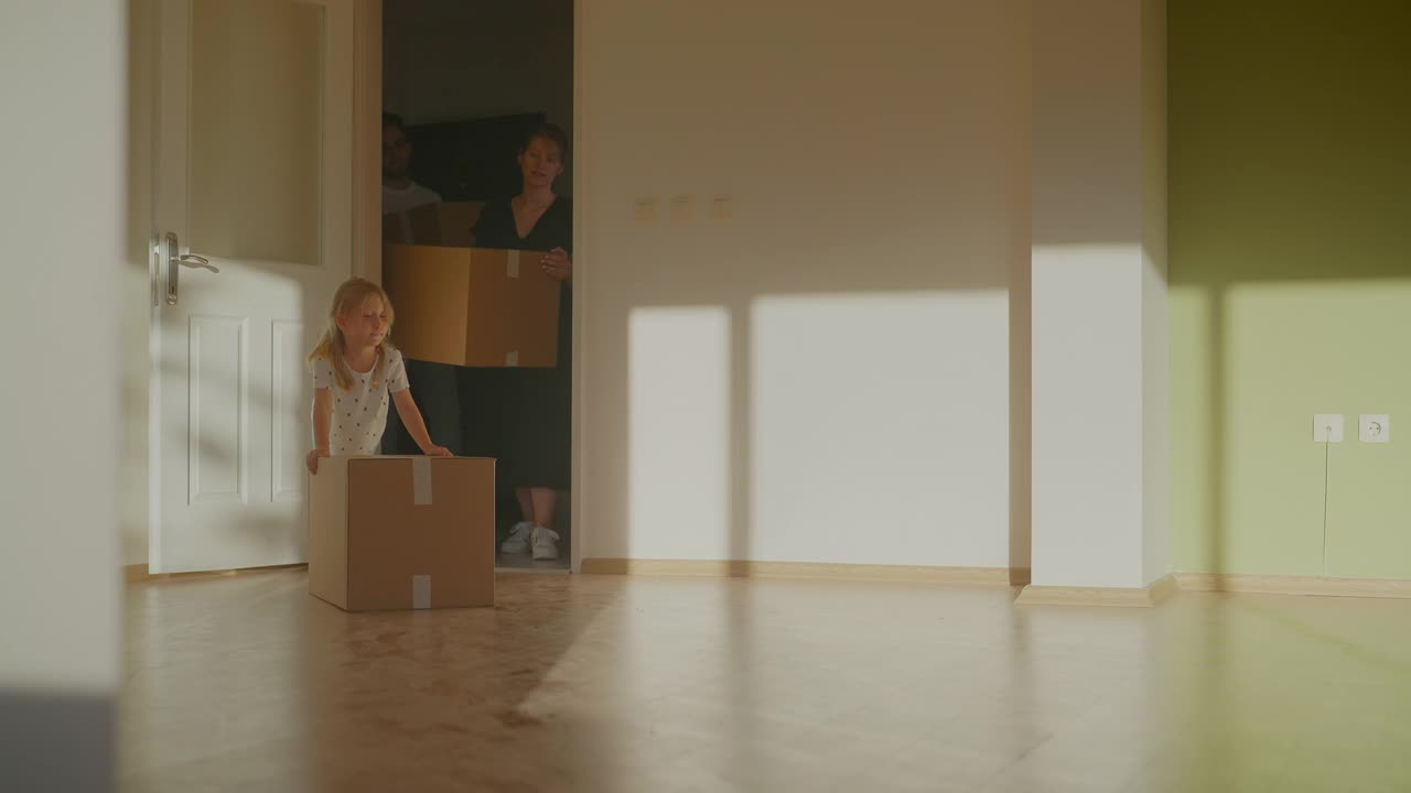 一个年轻的家庭带着一个孩子搬着纸板箱进了他们的新家视频素材
