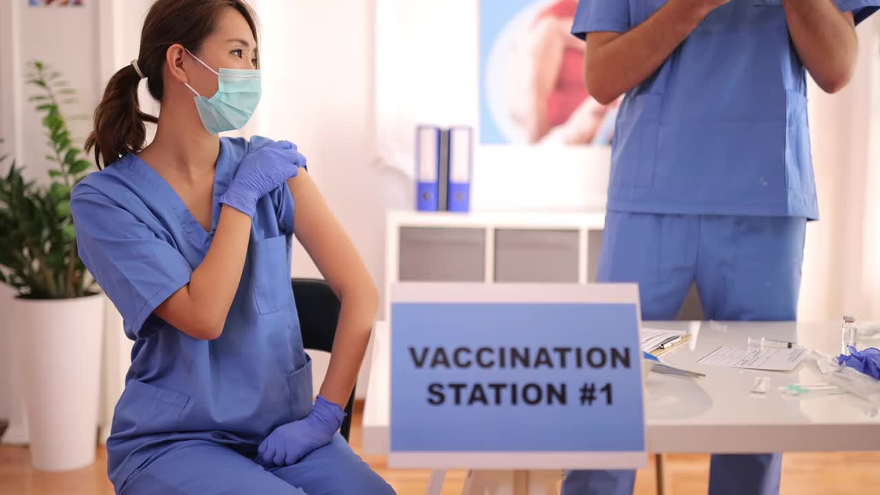 在Covid-19疫苗接种中心，女护士从她的同事那里接种疫苗视频素材