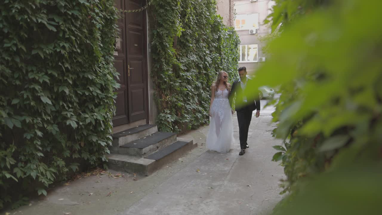 新娘和新郎手牵着手一起走在小巷里视频下载
