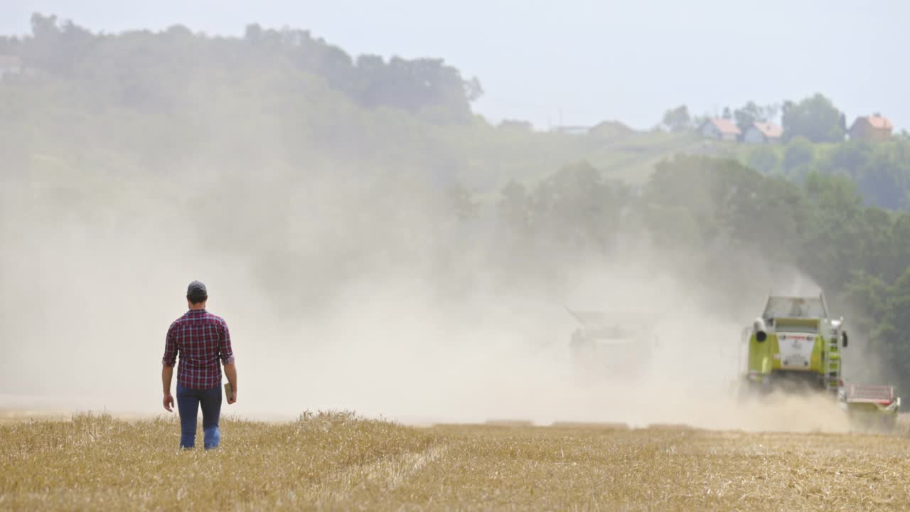 农民走在联合收割机后面收割小麦视频素材