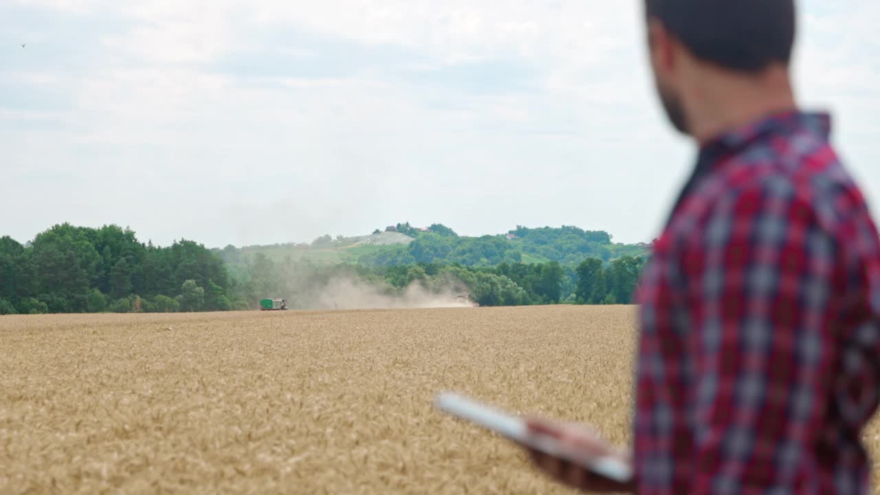 农夫在联合收割机收割小麦的同时使用数字平板电脑视频素材