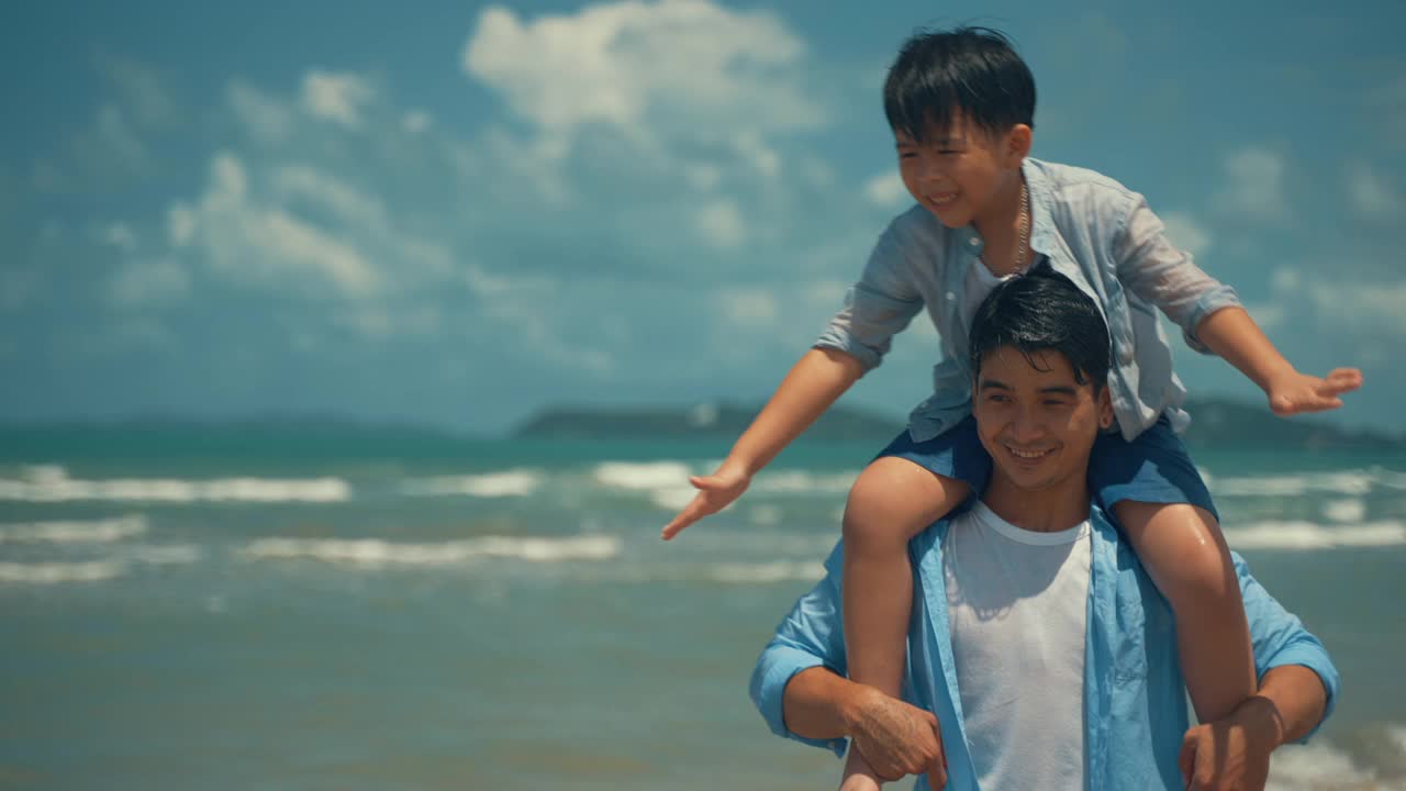 海滩上的幸福家庭。人们在暑假里玩得很开心。父亲、母亲和孩子背对着蓝色的大海和天空。假日旅行的概念视频素材
