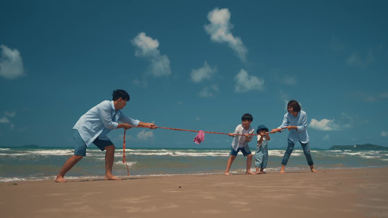 快乐的亚洲家庭在沙滩上玩拔河。人们的生活方式旅游度假的概念。视频素材
