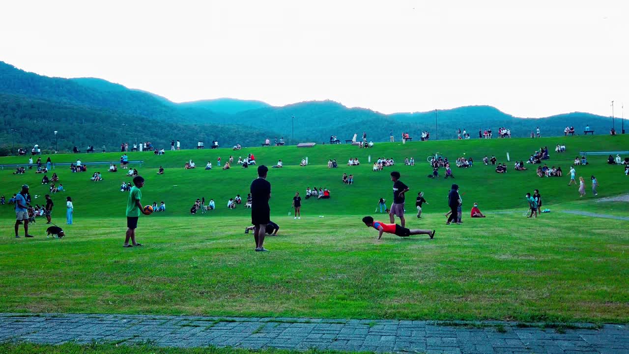 城市公共公园未被认识的人来此休闲放松，与山区背景保持社交距离视频素材