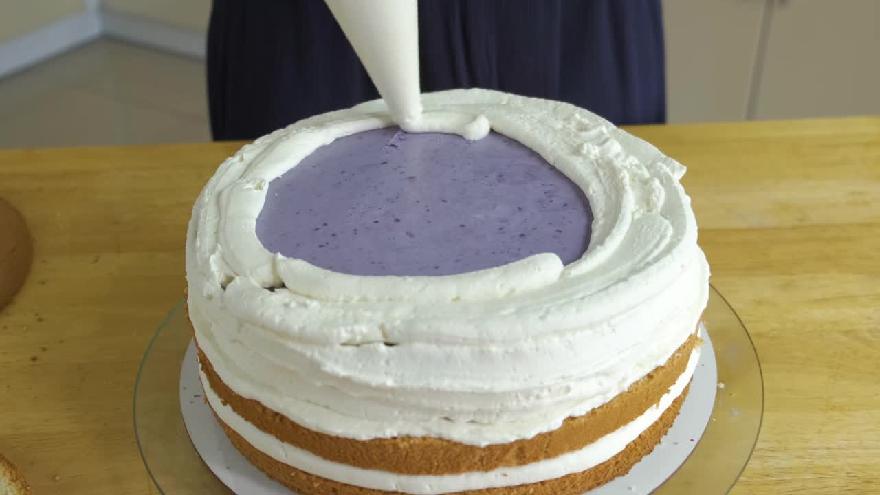 女人用白奶油和饼干制作甜蛋糕的特写镜头。视频下载