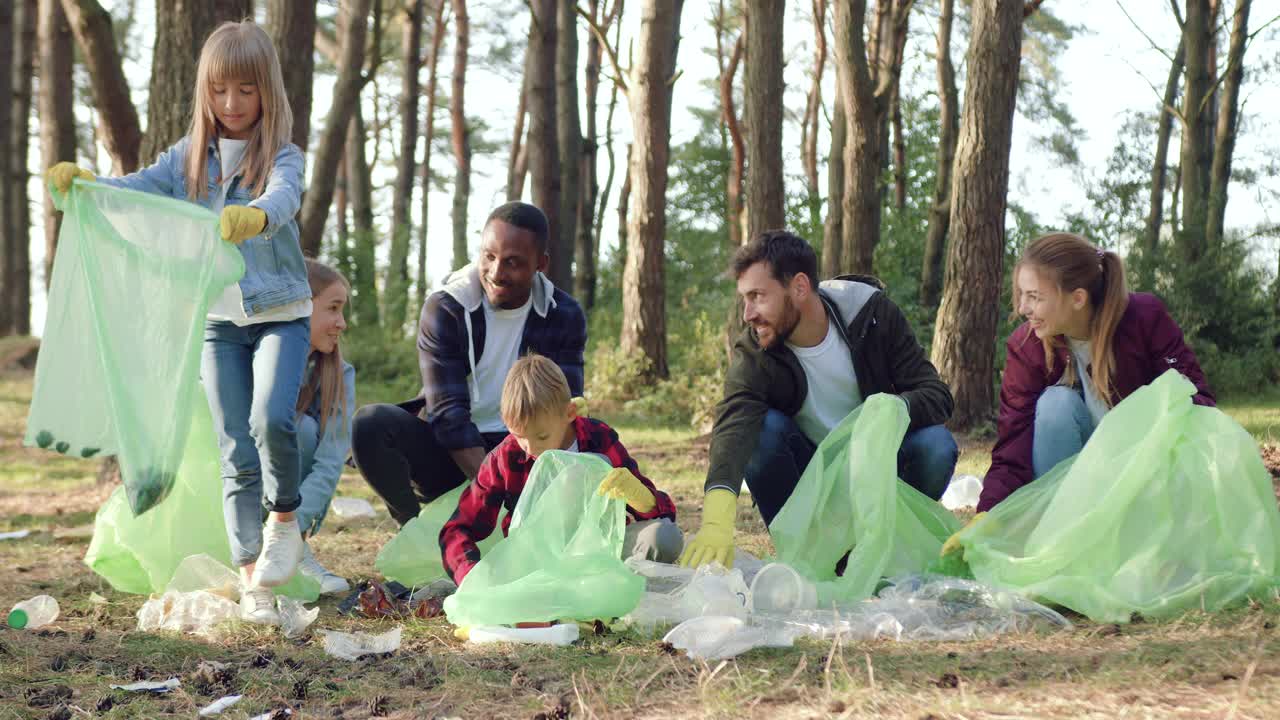 愉快满意的多种族的成年人和儿童积极分子团队在公园收集垃圾成塑料袋，保护环境的理念视频下载
