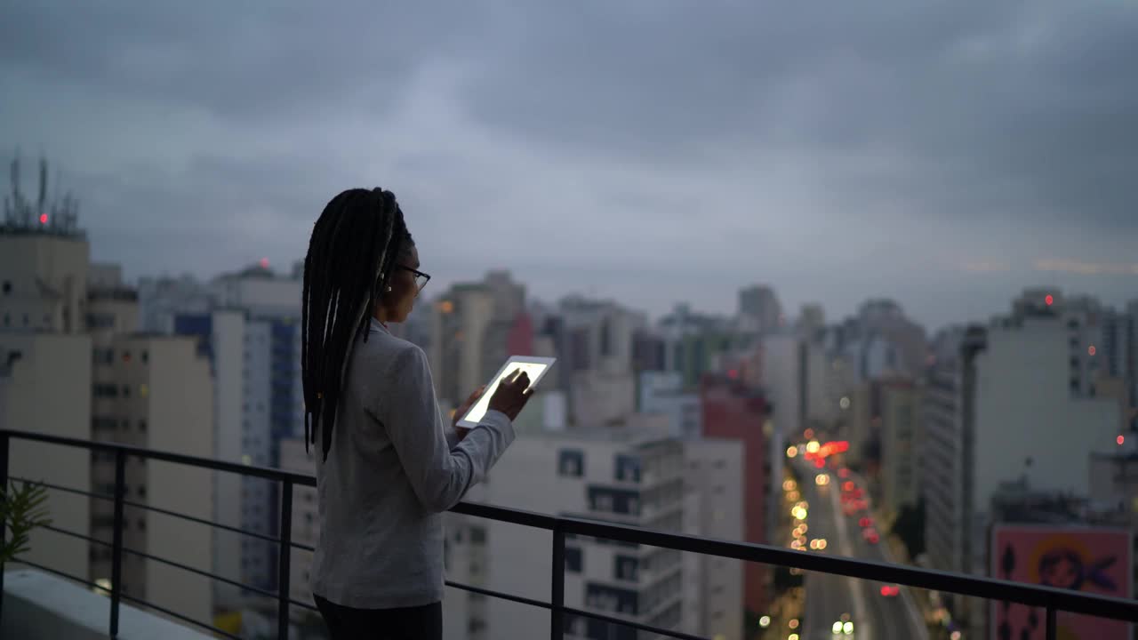 一位年轻的女商人在屋顶上思考和使用数字平板电脑视频素材