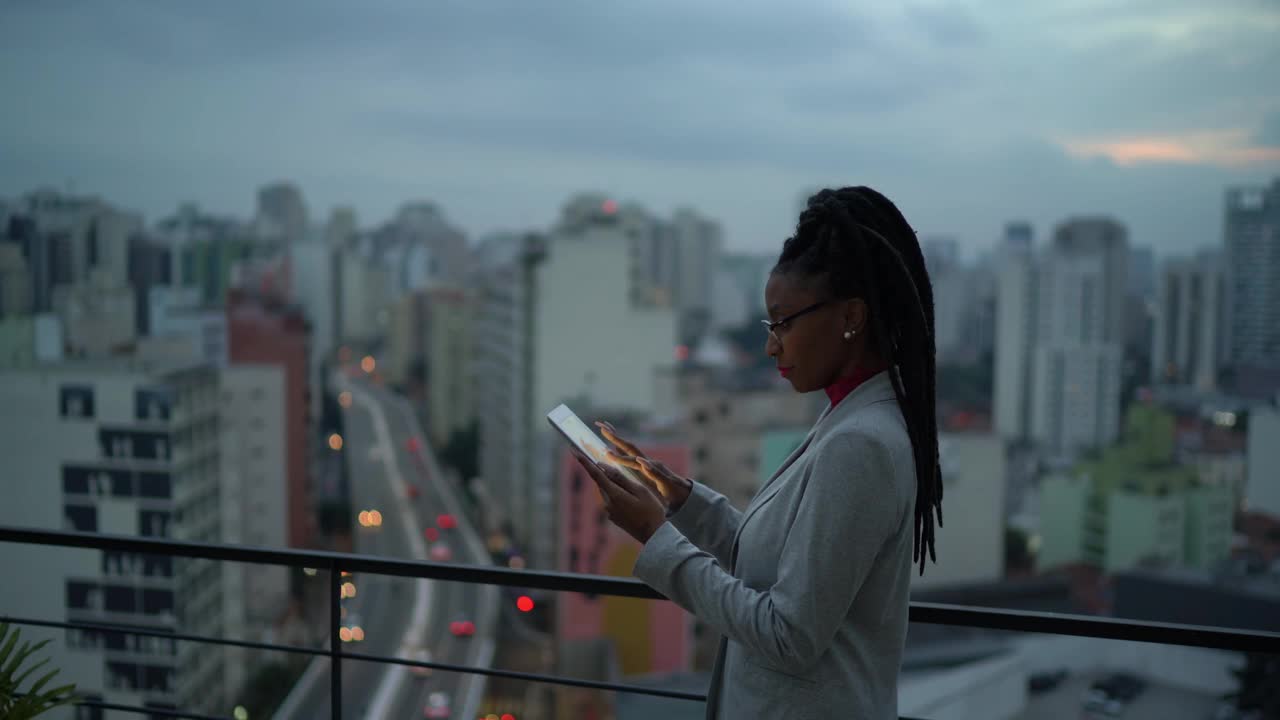 一位年轻的女商人在屋顶上思考和使用数字平板电脑视频素材