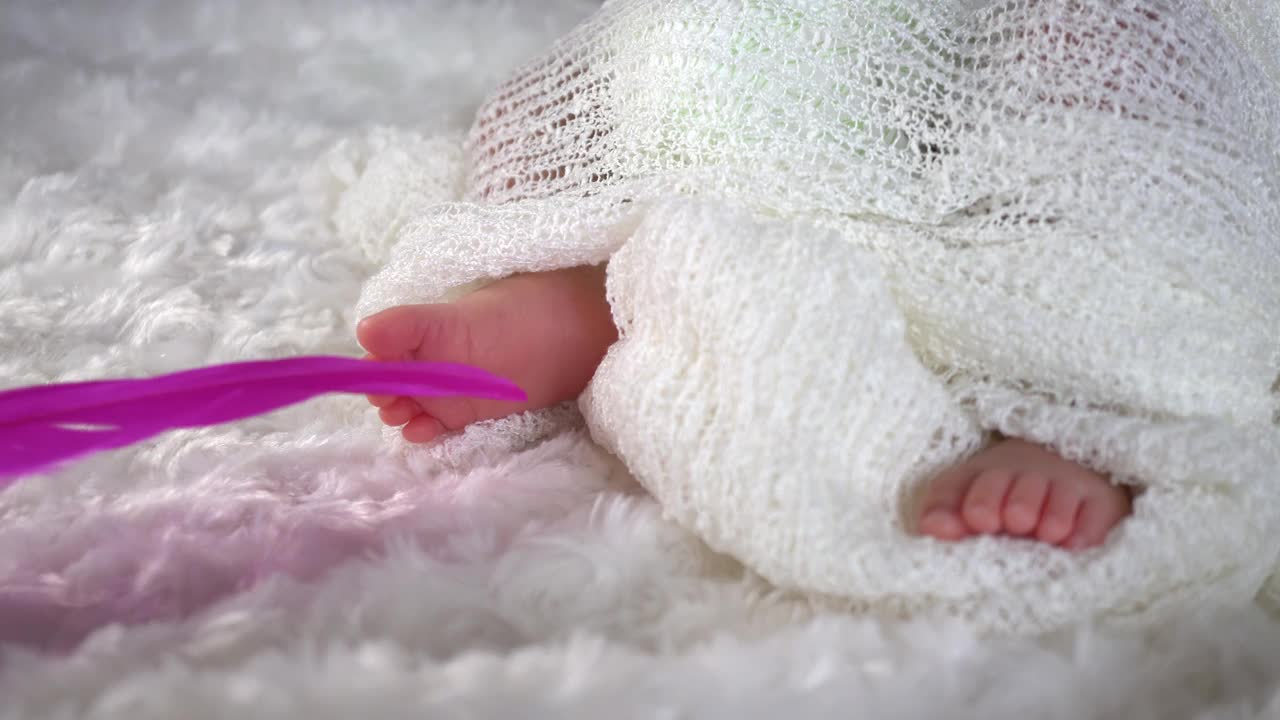 新生婴儿的腿沾着粉红色的羽毛视频下载
