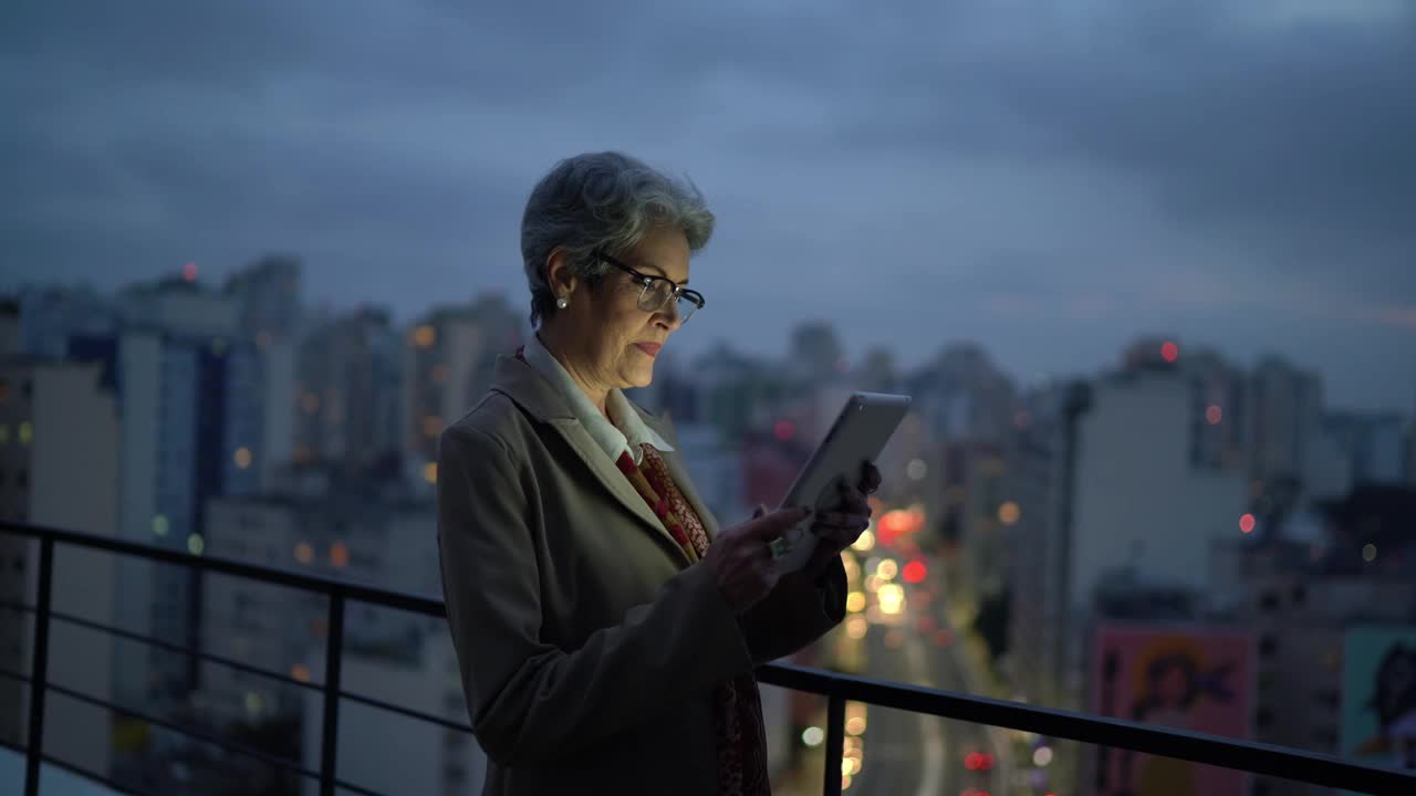 一位资深女商人在屋顶上使用数字平板电脑视频下载