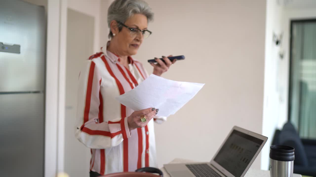 一位资深女性在家工作时用智能手机发语音信息视频素材
