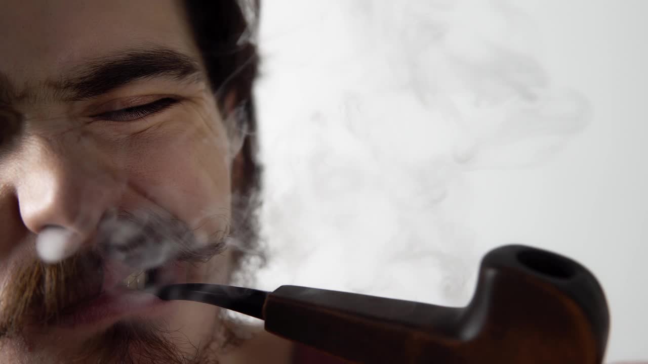 一个男人皱着眉头抽着烟斗，鼻孔里呼出一大堆烟视频下载