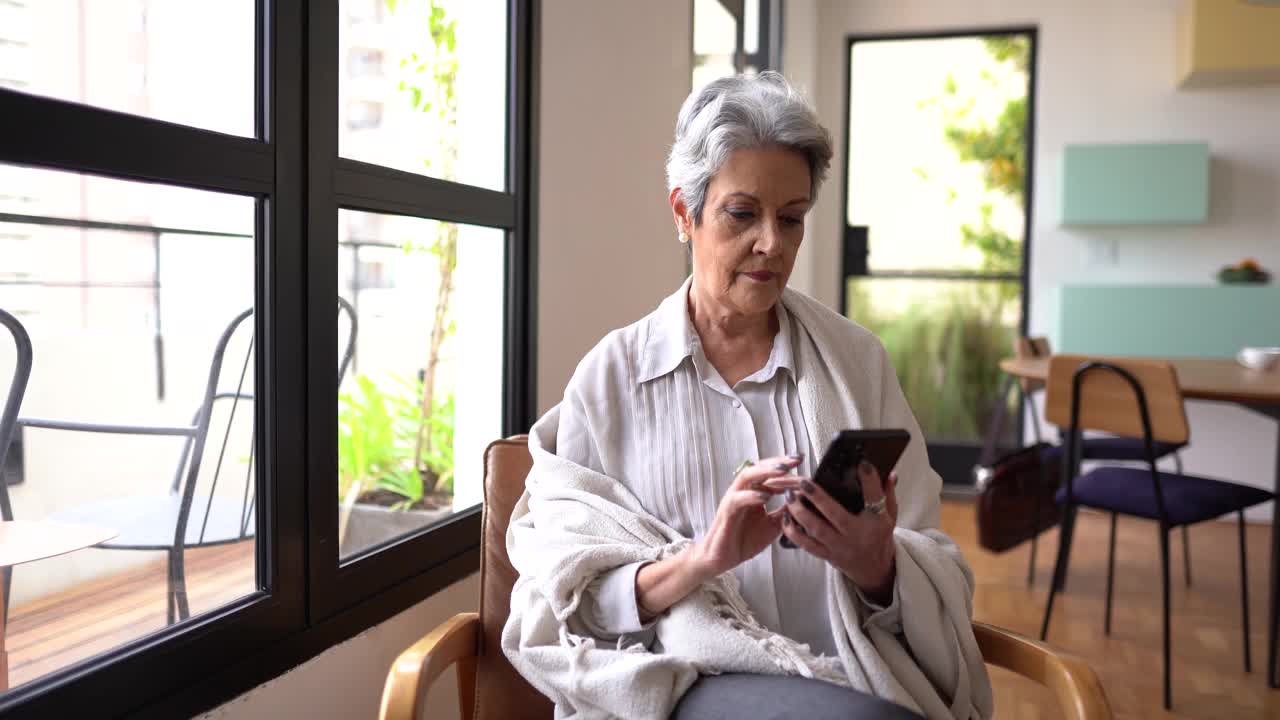 资深女性在家使用智能手机视频素材