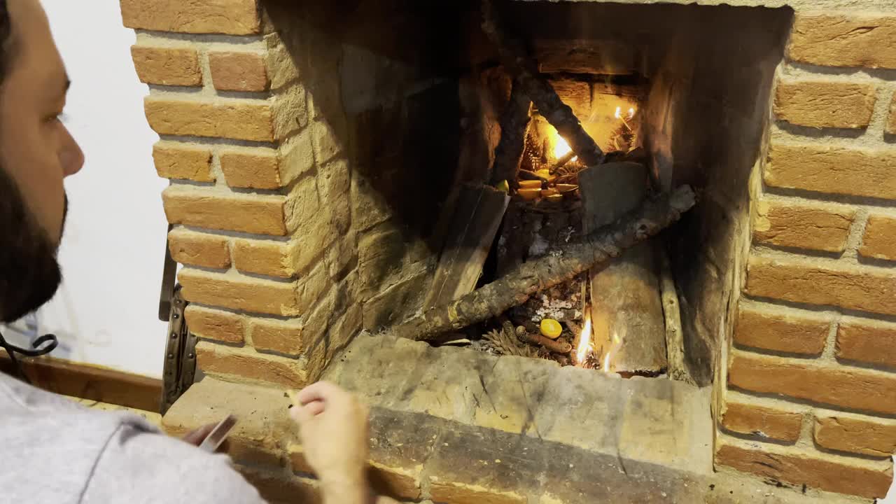 年轻人在冬天用火柴棍在砖墙壁炉前生火视频下载
