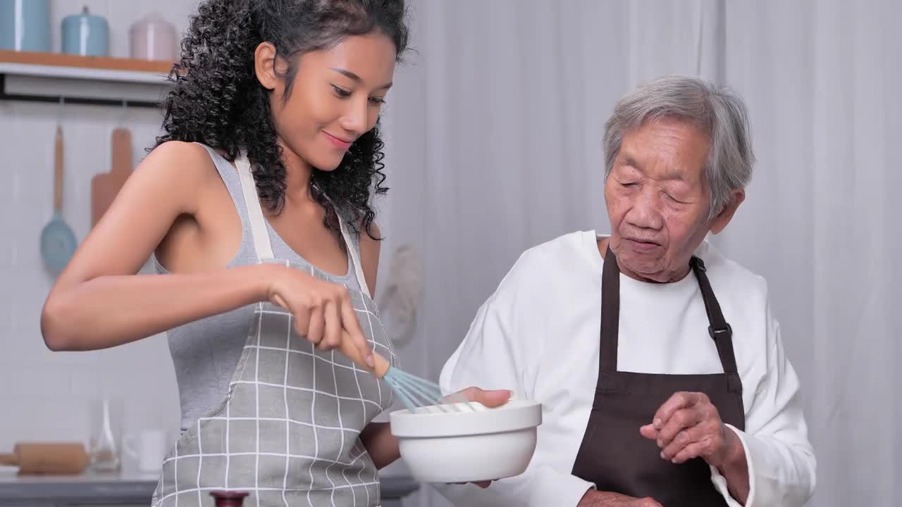拉丁美洲和西班牙裔的祖母，84岁，晚上在家里和她的孙女一起在厨房做饭。家庭关爱家庭的理念。视频下载