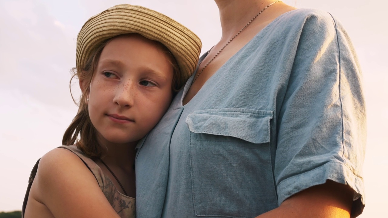 一个戴着帽子的美丽少女温柔地拥抱着她的母亲。女儿疼爱地拥抱着母亲的胸膛。父母和孩子之间的关系视频素材