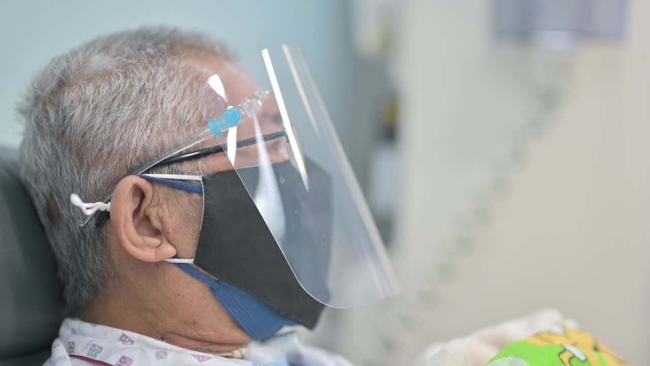 亚洲华人老人坐在椅子上，戴着面罩，正在医院接受透析治疗视频素材