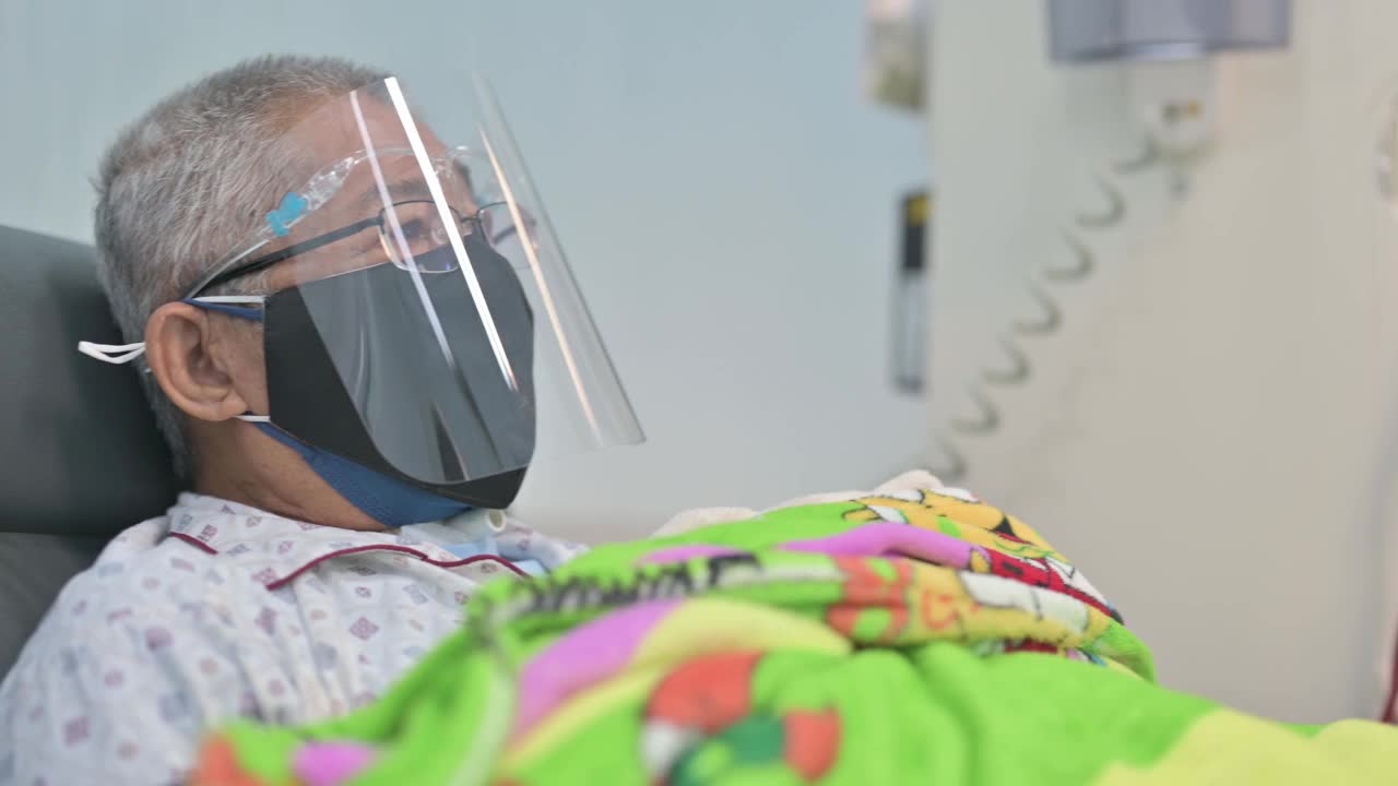 亚洲华人老人坐在椅子上，戴着面罩，正在医院接受透析治疗视频素材