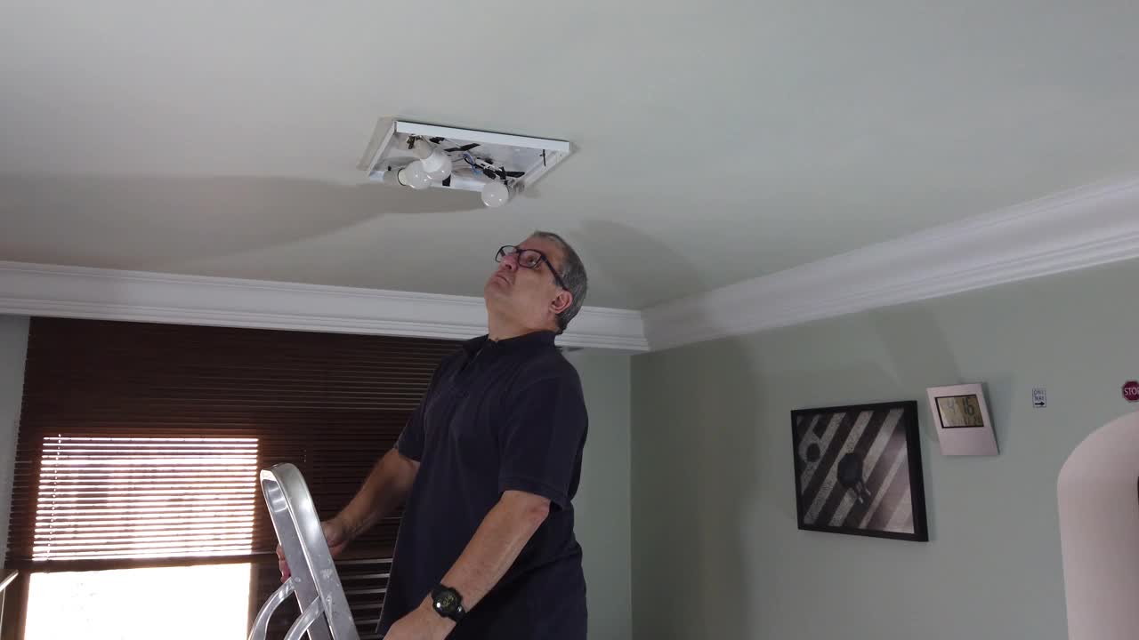 家居装饰-成年男子从天花板上取下灯视频下载
