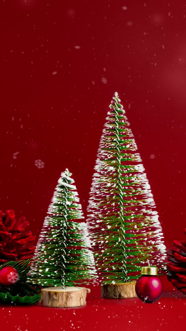 圣诞快乐，新年快乐与雪花飘落和红色背景与圣诞树和松果雪花视频下载