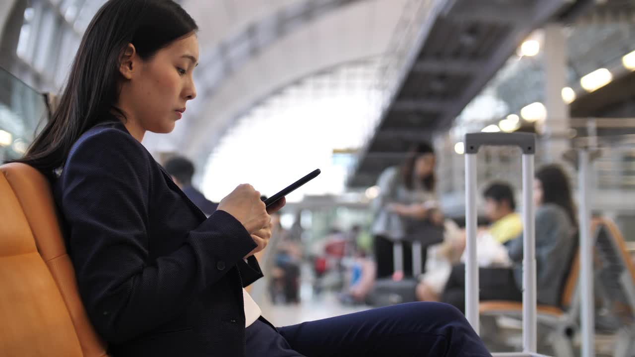 一个女人在机场用智能手机视频下载