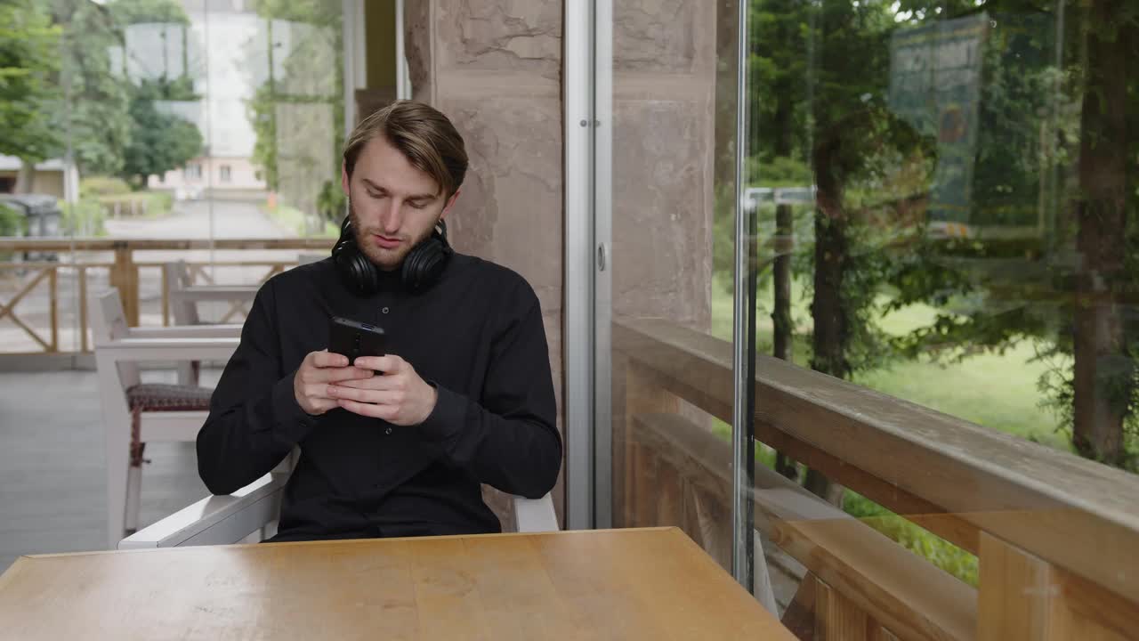 年轻人拿着智能手机坐在椅子上发短信视频素材