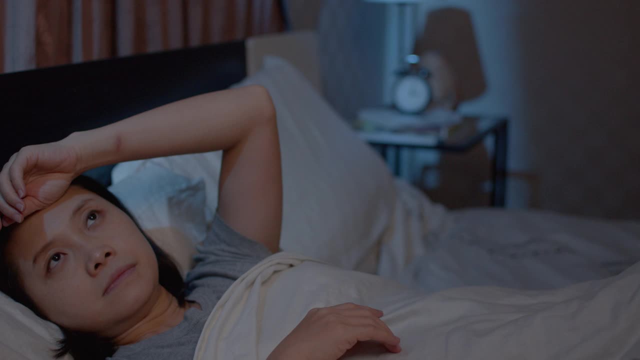 抑郁的亚洲女性不能睡在床上。失眠综合症无眠视频素材