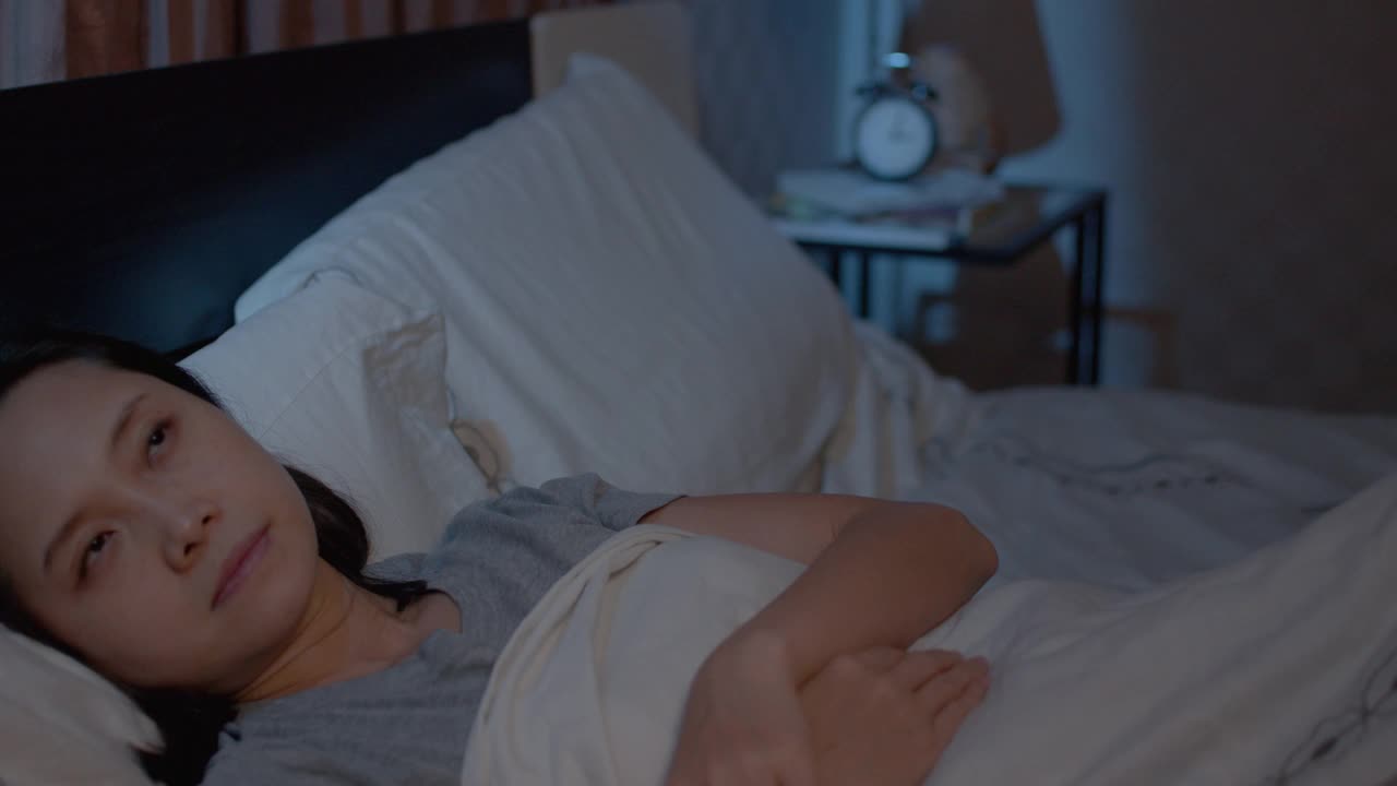 抑郁的亚洲女性不能睡在床上。失眠综合症无眠视频素材