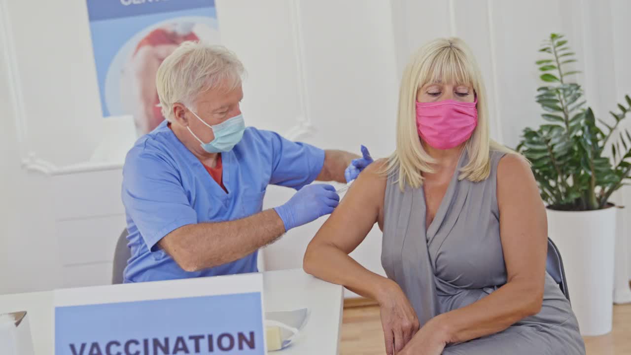 医护人员在疫苗接种中心为妇女注射新冠疫苗视频下载