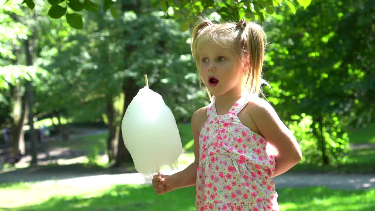 可爱的小女孩在公园里吃棉花糖视频素材