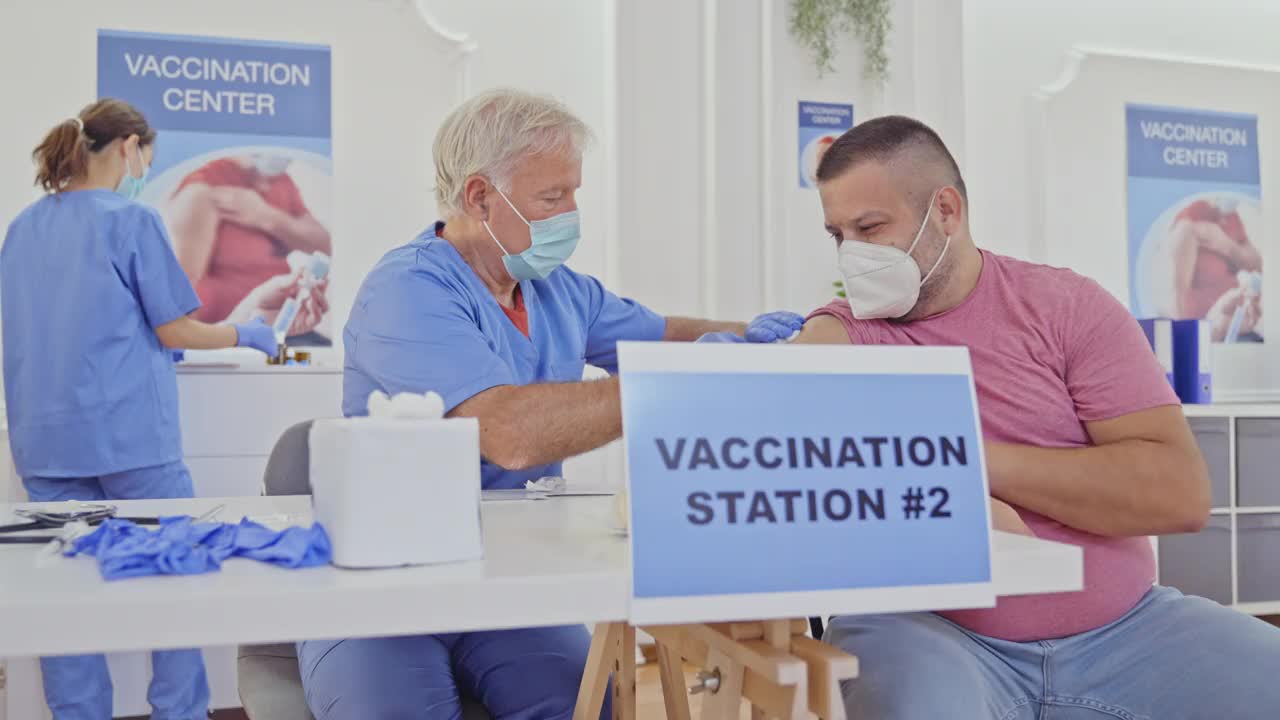 卫生保健人员在疫苗接种中心向人群注射新冠疫苗视频下载