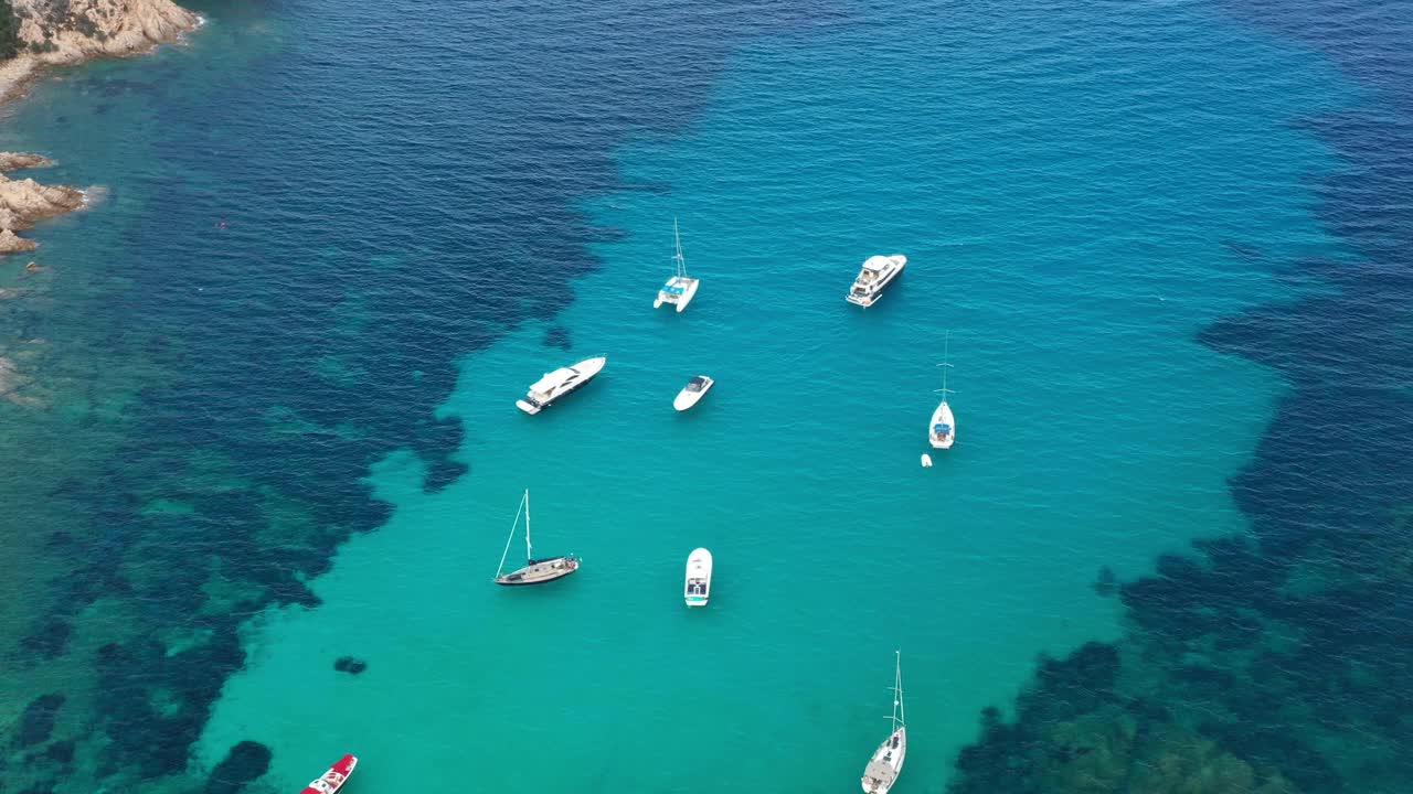 在阳光明媚的日子里，从上面看，令人惊叹的鸟瞰图，一些船漂浮在绿松石般清澈的水面上。意大利撒丁岛的翡翠海岸。视频素材