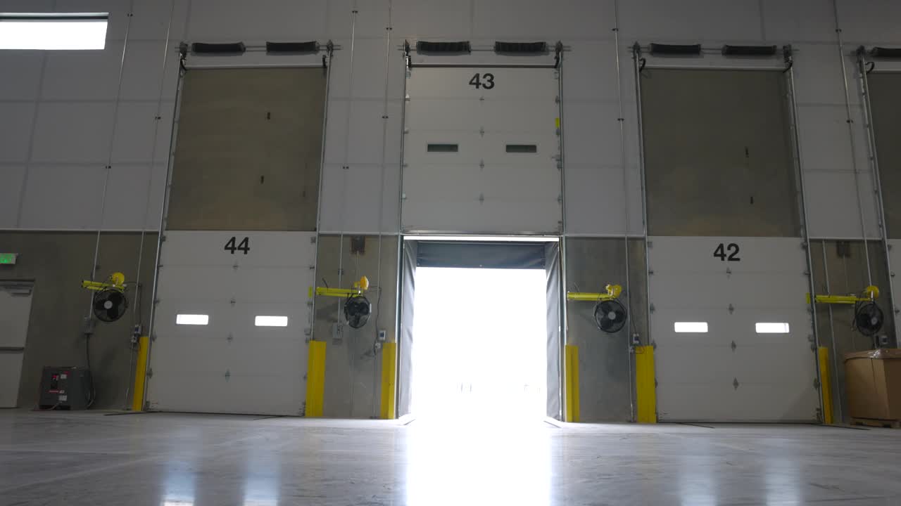 极端宽镜头的男性仓库工作人员行走和关闭装卸门的仓库视频素材
