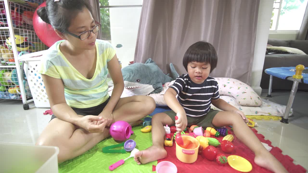 母亲和儿子一起在家里的客厅里玩玩具视频下载
