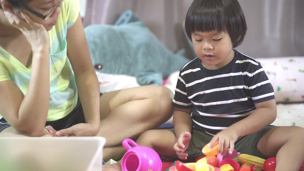 母亲和儿子一起在家里的客厅里玩玩具视频下载