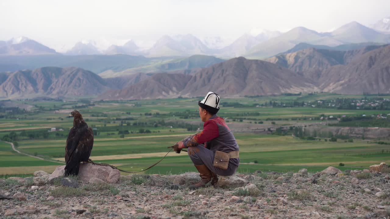 鹰猎人坐在吉尔吉斯斯坦山脉的背景视频素材