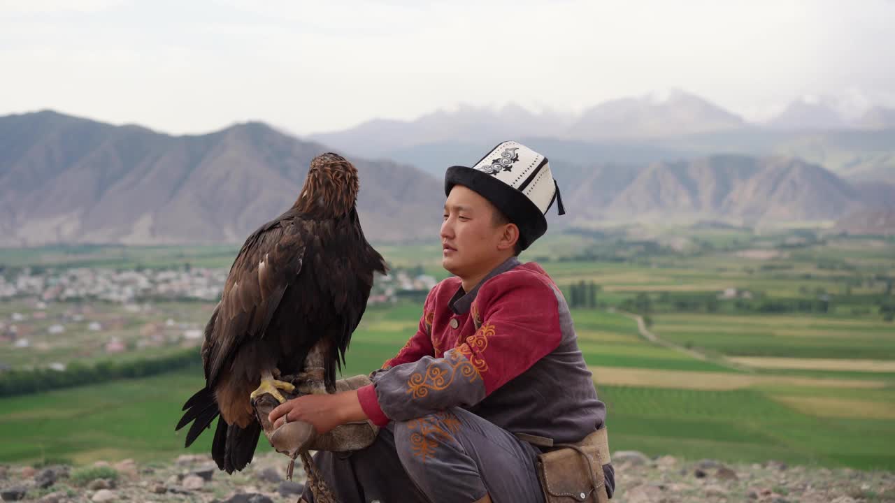 鹰猎人坐在吉尔吉斯斯坦山脉的背景视频素材
