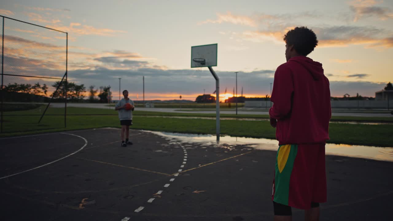 两个十几岁的男孩在日落时分打篮球视频素材