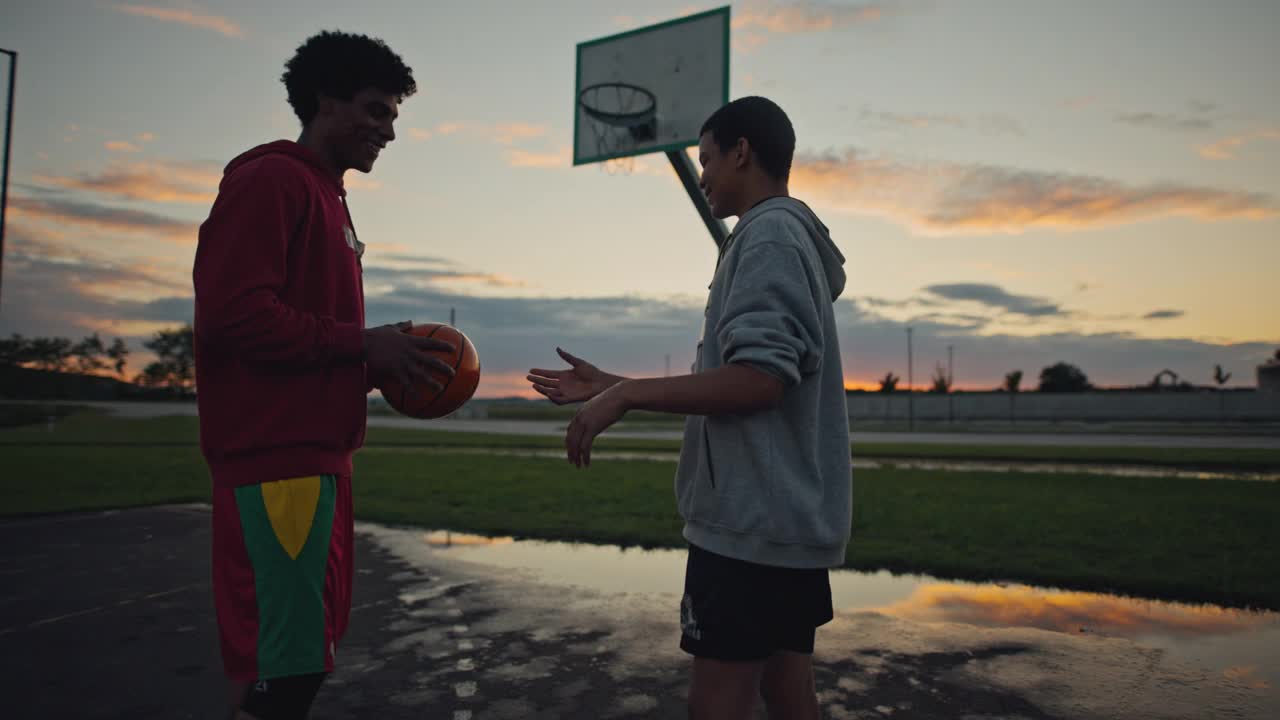 两个年轻的篮球运动员在篮球场上打篮球视频素材