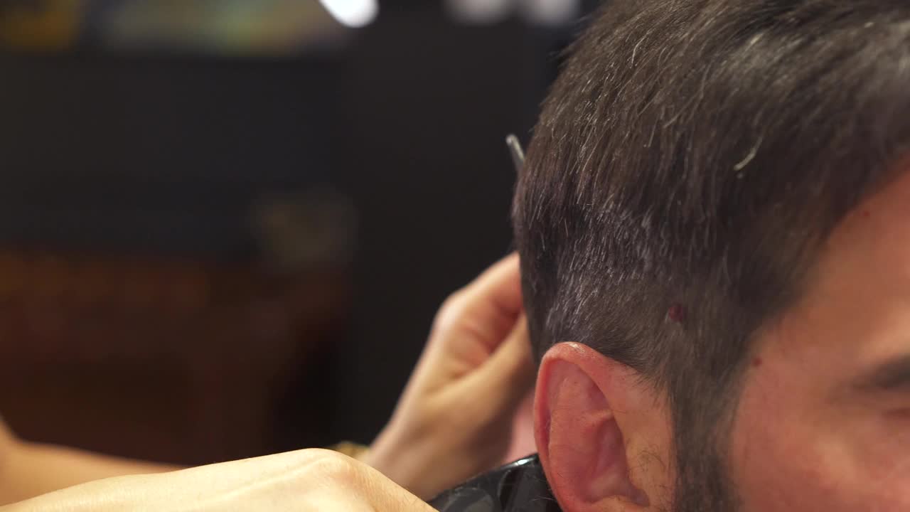 理发师用梳子和剪刀理发。框架。一名男子在理发店剪时髦发型的特写镜头视频素材