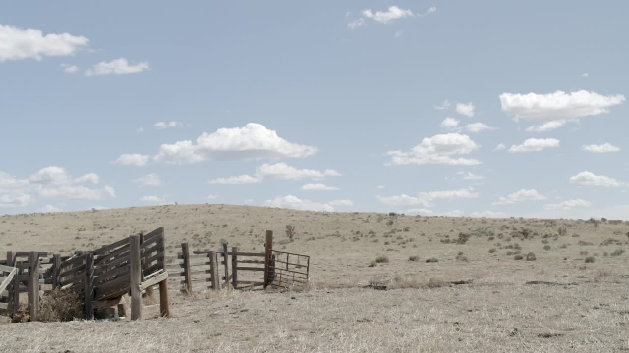 沙漠景观的广角灌木可见。蓝天白云可见。在fg中可见的木栅栏或马场。可能是农场。美国西南部，可能是亚利桑那州。视频下载