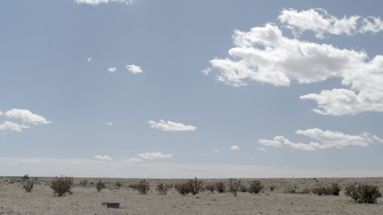 Pan从左到右的广角沙漠景观与灌木可见。蓝天白云可见。美国西南部，可能是亚利桑那州。视频下载