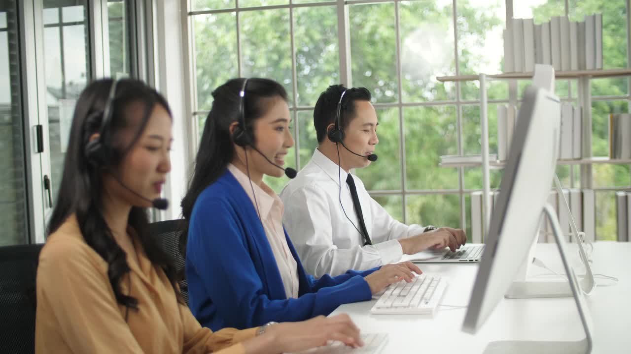 亚洲女性呼叫中心代理与客户在她的工作站交谈视频素材