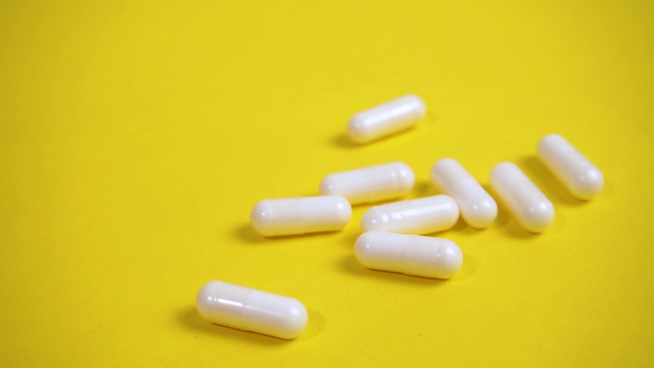 白色药丸，黄色背景上的胶囊视频下载
