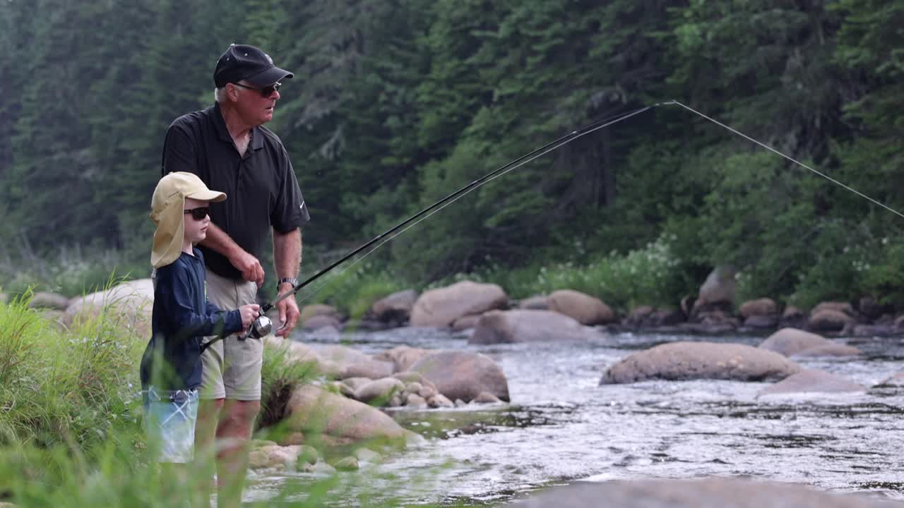 可爱的红发男孩和爷爷在魁北克的河里钓鱼视频素材